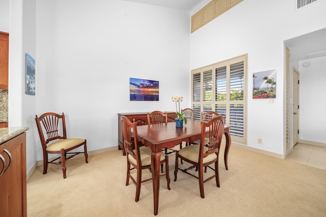 carpeted dining room featuring a high ceiling