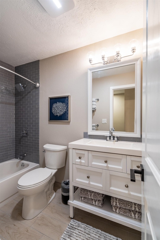 full bathroom with tiled shower / bath, vanity, toilet, and a textured ceiling