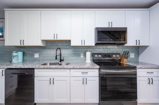 kitchen featuring sink, appliances with stainless steel finishes, white cabinetry, light stone countertops, and decorative backsplash