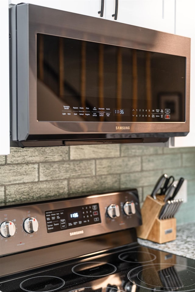 details with tasteful backsplash, electric range oven, and white cabinets