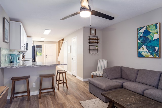 living room featuring ceiling fan, sink, and light hardwood / wood-style flooring