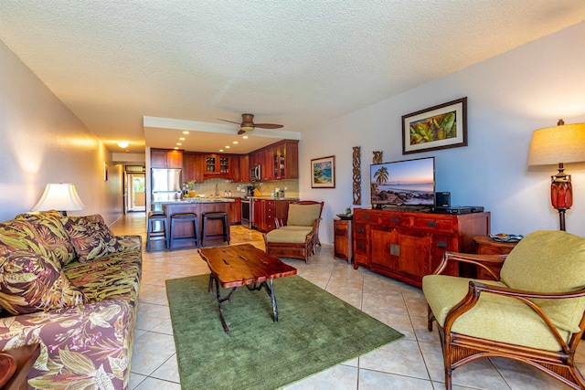 living area featuring light tile patterned floors, a ceiling fan, and a textured ceiling