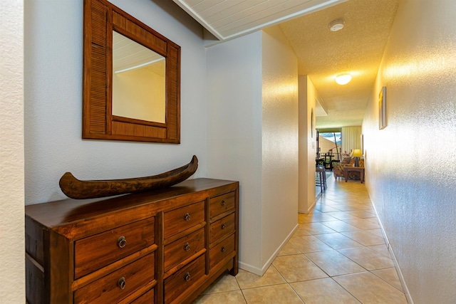 hall featuring light tile patterned floors and baseboards