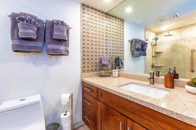 bathroom featuring vanity, visible vents, toilet, and a tile shower