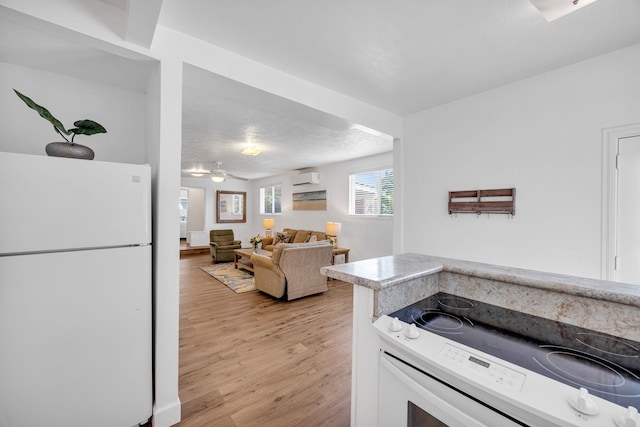 317 Kenolio Rd, Kihei, HI 96753 - kitchen with light countertops, a ceiling fan, a wall unit AC, white appliances, and light wood-style floors