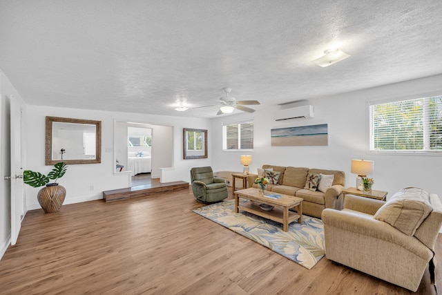 317 Kenolio Rd, Kihei, HI 96753 - living room with a wall unit AC, baseboards, a textured ceiling, a ceiling fan, and wood finished floors