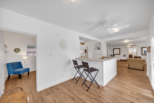 317 Kenolio Rd, Kihei, HI 96753 - kitchen featuring a breakfast bar area, light wood-type flooring, a sink, ceiling fan, and freestanding refrigerator