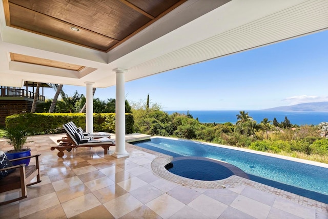 view of swimming pool featuring an in ground hot tub, a water view, and a patio