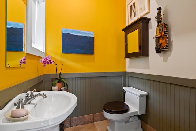 bathroom with toilet, sink, and tile flooring