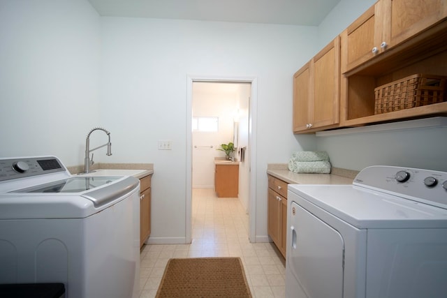 laundry room featuring washing machine and clothes dryer, cabinets, and sink