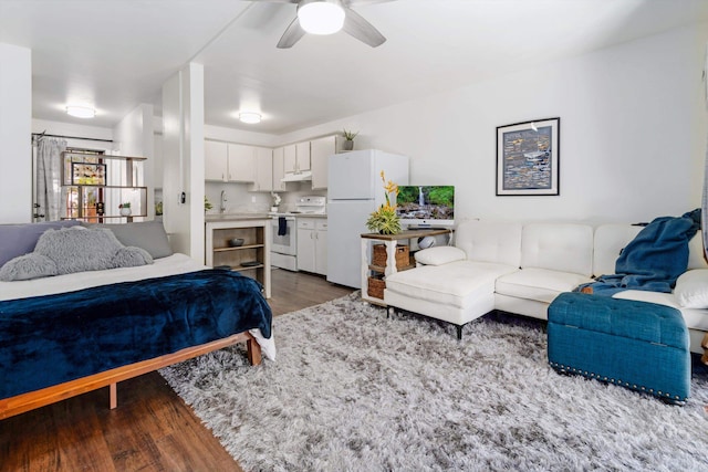 bedroom featuring dark wood-type flooring, ceiling fan, and white fridge