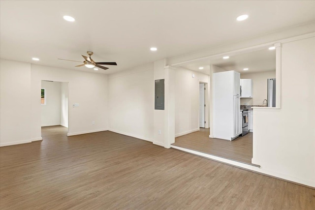 unfurnished living room with ceiling fan, sink, dark wood-type flooring, and electric panel