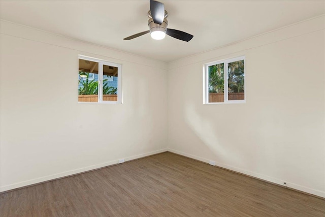 unfurnished room featuring a wealth of natural light, dark wood-type flooring, and ceiling fan