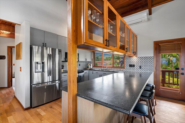 41 Pihaa St, Lahaina, HI 96761 - kitchen featuring stainless steel refrigerator with ice dispenser, dark countertops, light wood finished floors, a wall mounted AC, and a peninsula