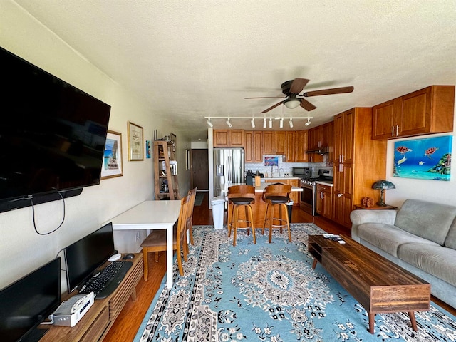 living room with light hardwood / wood-style floors, track lighting, a textured ceiling, and ceiling fan