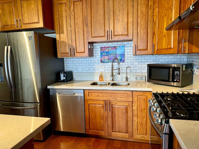 kitchen featuring tasteful backsplash, range hood, sink, stainless steel appliances, and dark hardwood / wood-style floors