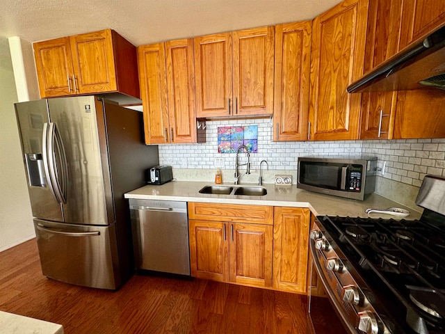 kitchen with dark wood-type flooring, sink, backsplash, appliances with stainless steel finishes, and premium range hood