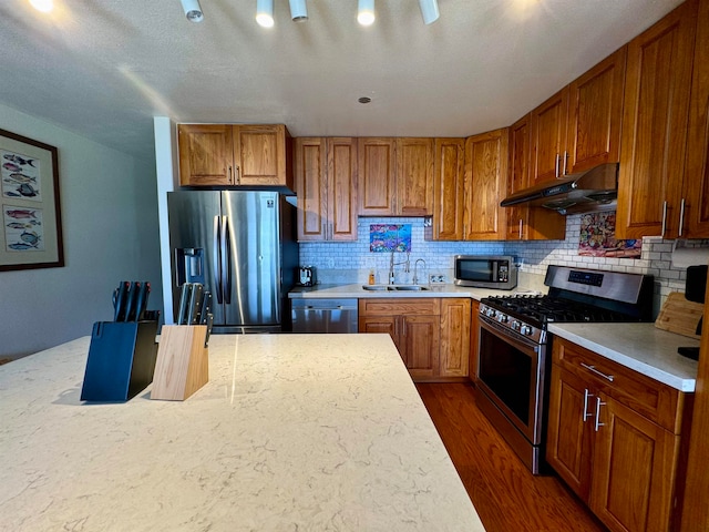 kitchen featuring sink, a textured ceiling, backsplash, dark wood-type flooring, and stainless steel appliances