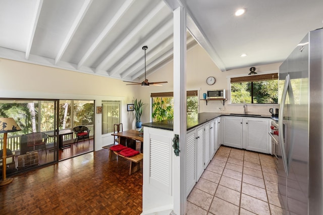 kitchen featuring ceiling fan, sink, vaulted ceiling with beams, light parquet flooring, and appliances with stainless steel finishes