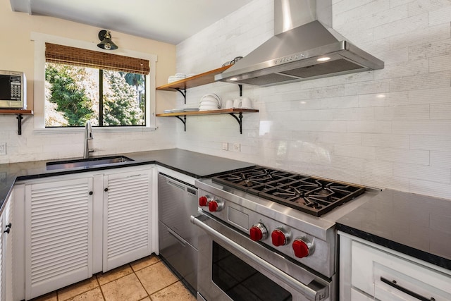 kitchen with wall chimney range hood, sink, tasteful backsplash, white cabinetry, and stainless steel appliances