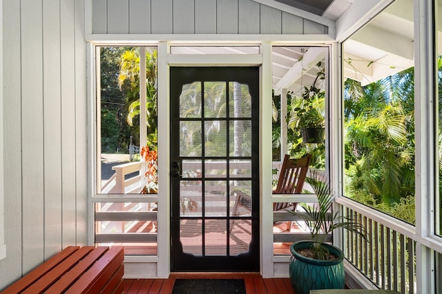 doorway to outside with hardwood / wood-style floors, lofted ceiling, and wood walls