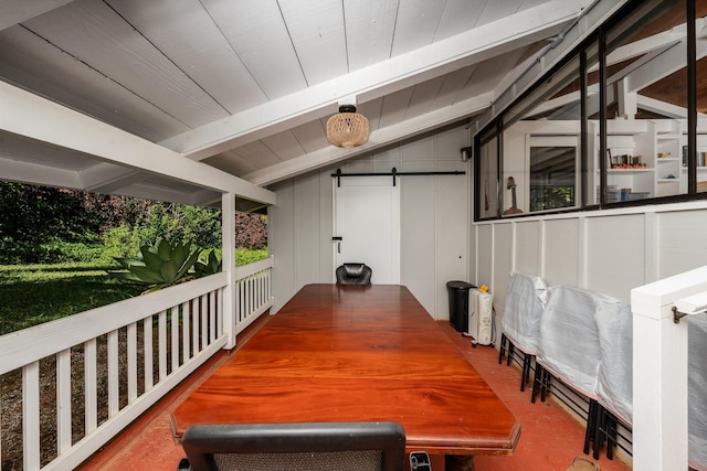 dining room with lofted ceiling with beams, a barn door, and wooden walls