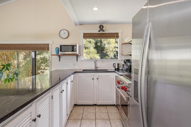 kitchen featuring sink, dark stone countertops, appliances with stainless steel finishes, tasteful backsplash, and white cabinetry