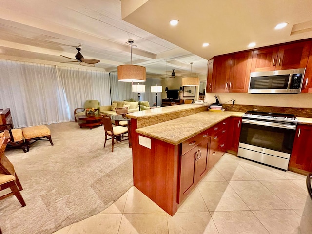 kitchen with hanging light fixtures, gas range, light stone counters, ceiling fan, and kitchen peninsula