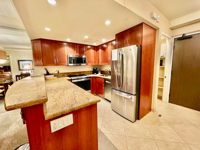 kitchen with sink, light tile floors, light stone counters, appliances with stainless steel finishes, and a breakfast bar