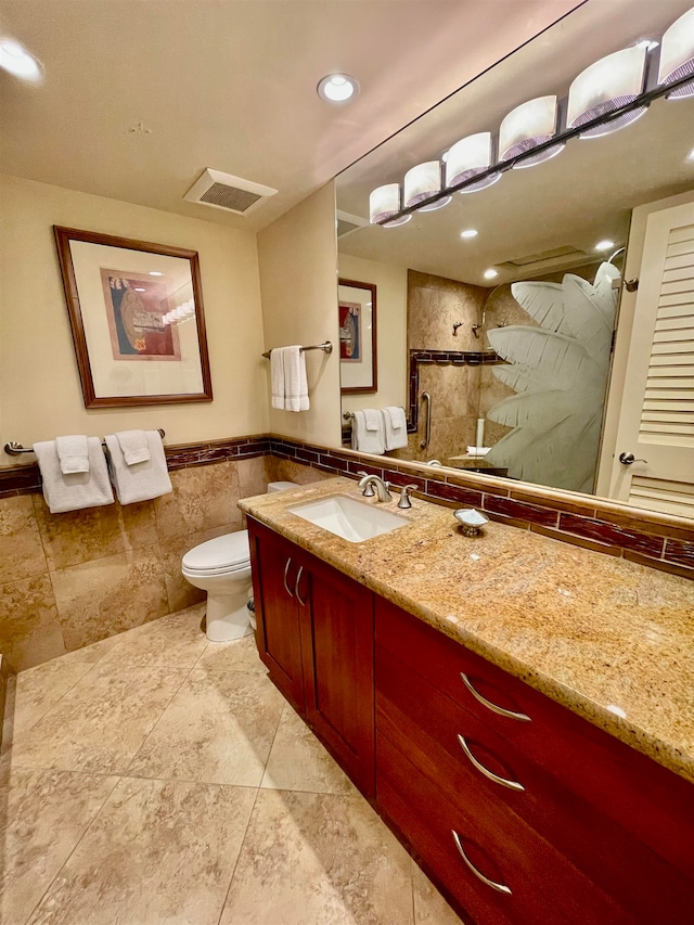 bathroom with tile flooring, oversized vanity, toilet, and tile walls