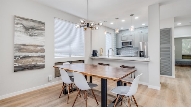 dining area featuring sink, light hardwood / wood-style flooring, and a notable chandelier