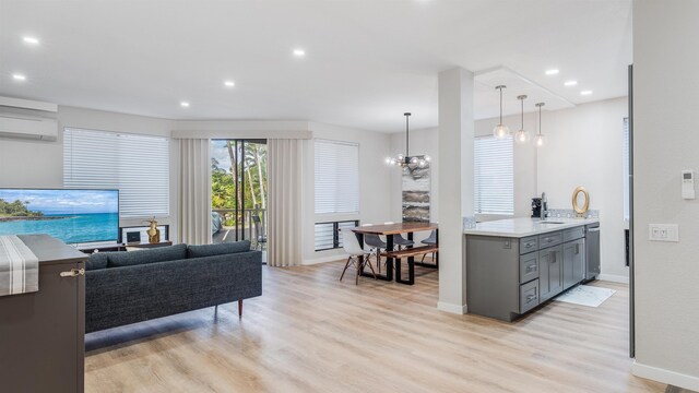 living room with a chandelier, light hardwood / wood-style flooring, and a wall mounted AC