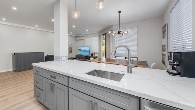 kitchen featuring light stone countertops, pendant lighting, sink, gray cabinets, and a wall unit AC