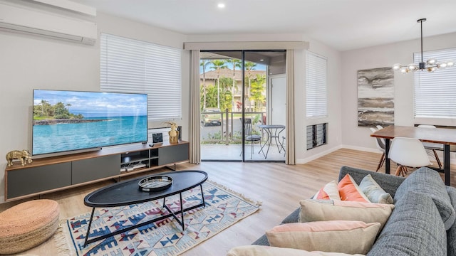 living room with light hardwood / wood-style floors, a chandelier, and a wall mounted air conditioner