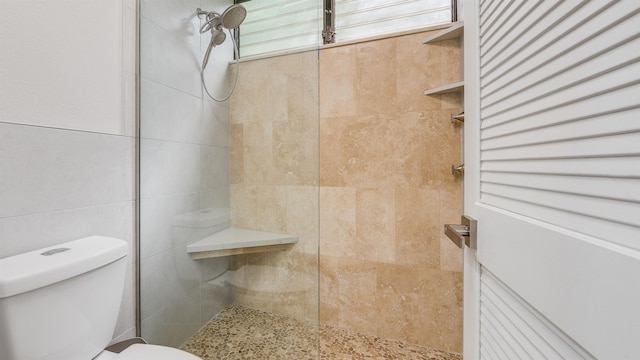 bathroom with toilet, tile walls, and a tile shower