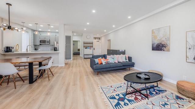 living room featuring sink, an inviting chandelier, and light hardwood / wood-style flooring