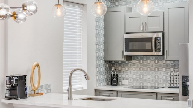 kitchen with black electric cooktop, sink, decorative light fixtures, backsplash, and gray cabinets