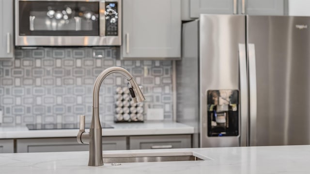 room details featuring backsplash, appliances with stainless steel finishes, and gray cabinetry