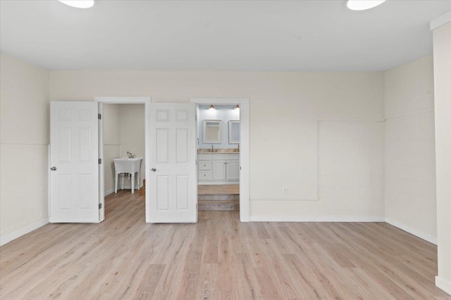 unfurnished bedroom featuring sink, connected bathroom, and light hardwood / wood-style flooring