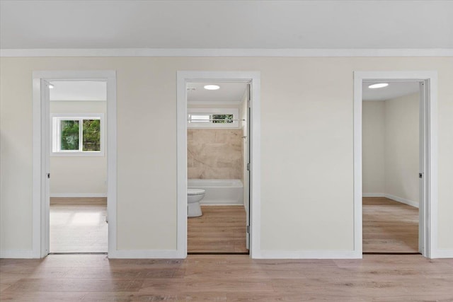 unfurnished bedroom featuring a closet, light wood-type flooring, and ensuite bath