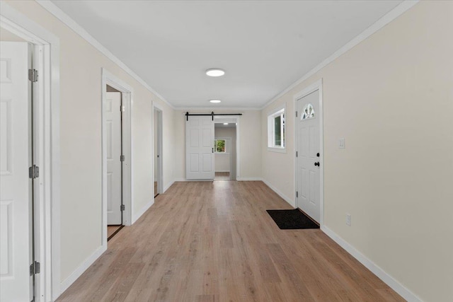 hall featuring ornamental molding, light hardwood / wood-style flooring, and a barn door