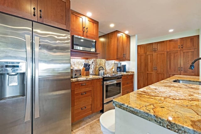 kitchen featuring appliances with stainless steel finishes, sink, tasteful backsplash, light stone counters, and light tile patterned flooring