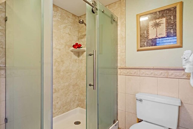 bathroom with toilet, tile walls, and an enclosed shower