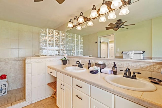 bathroom with a shower, tile walls, tile patterned floors, vanity, and ceiling fan