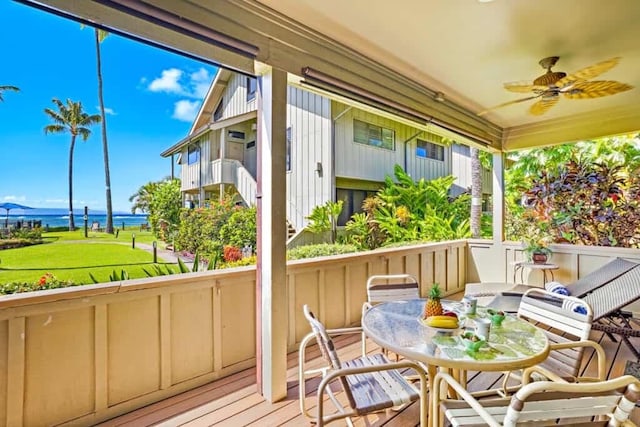 sunroom / solarium featuring ceiling fan and a water view