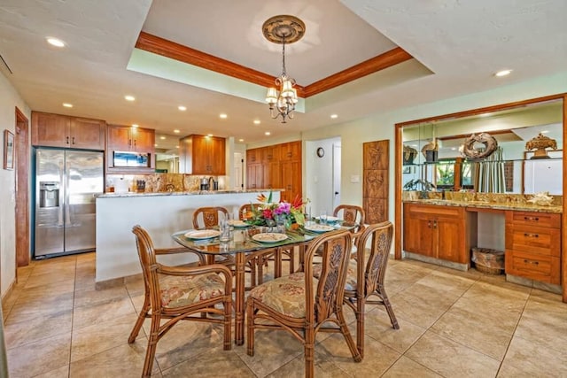 tiled dining space with a chandelier, crown molding, and a tray ceiling