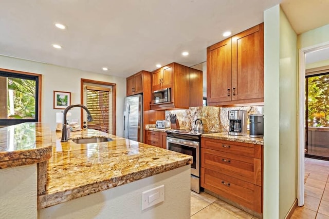 kitchen with appliances with stainless steel finishes, tasteful backsplash, sink, light tile patterned flooring, and light stone counters