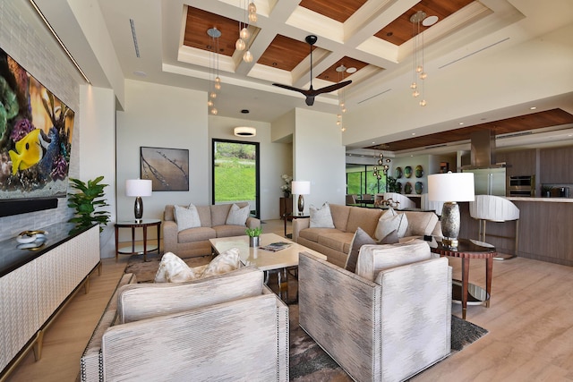 living room featuring coffered ceiling, light hardwood / wood-style flooring, a towering ceiling, and beam ceiling