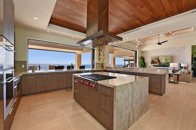 kitchen featuring light stone counters, wood ceiling, a kitchen island, island range hood, and stainless steel appliances