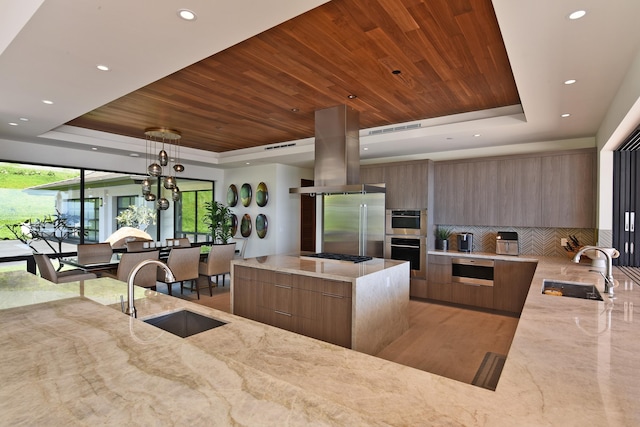 kitchen featuring decorative backsplash, a tray ceiling, pendant lighting, and sink